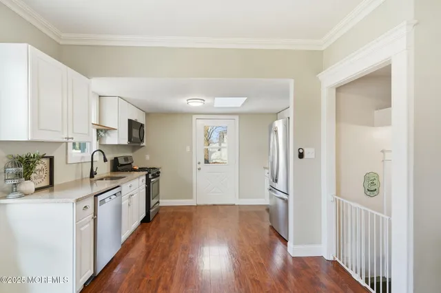 a kitchen with a refrigerator a sink and wooden floor