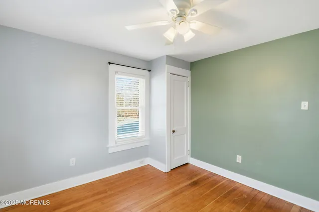 a view of an empty room with window and chandelier fan