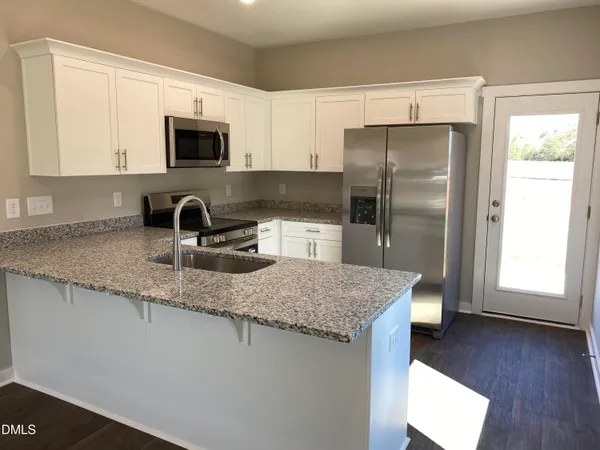 a kitchen with stainless steel appliances granite countertop a sink refrigerator and microwave