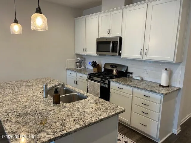 a kitchen with stainless steel appliances granite countertop a sink stove and cabinets