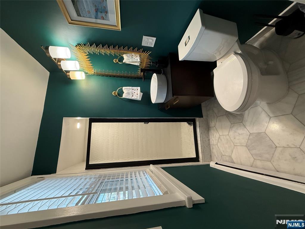 675 Center Street Oradell, NJ 07649 - Photo 16 of 29 a white toilet sitting next to a bathroom sink and a mirror