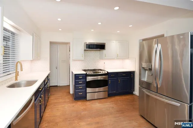 a kitchen with stainless steel appliances granite countertop a refrigerator a sink and a stove