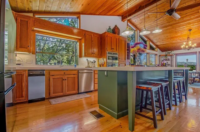 a kitchen with stainless steel appliances granite countertop a stove a refrigerator a dining table and chairs with wooden floor