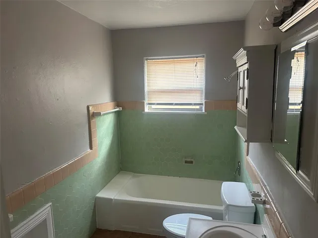 a bathroom with a toilet bathtub window and shower