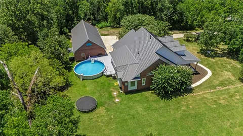 a aerial view of a house with a yard and trees all around