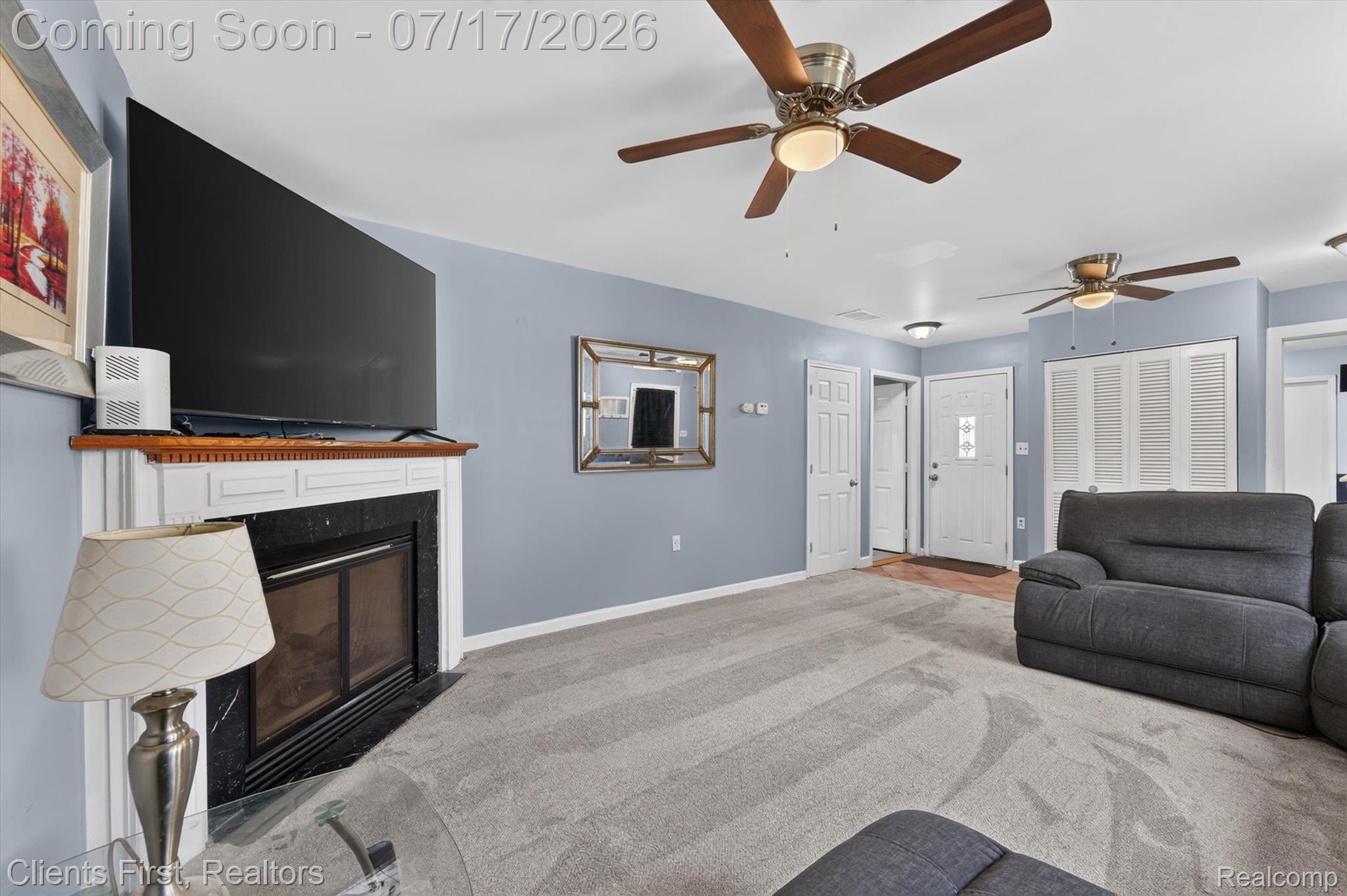 36852 Chase Street Romulus, MI 48174 - Photo 7 of 40 Living area featuring a fireplace with a white mantel and dark surround, light blue wall paint, and grey carpeting