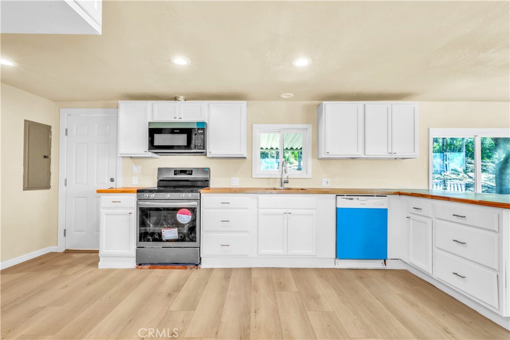 15905 Kugelman Street Lower Lake, CA 95457 - Photo 35 of 75 a kitchen with granite countertop a stove top oven a sink dishwasher and a microwave with wooden floor