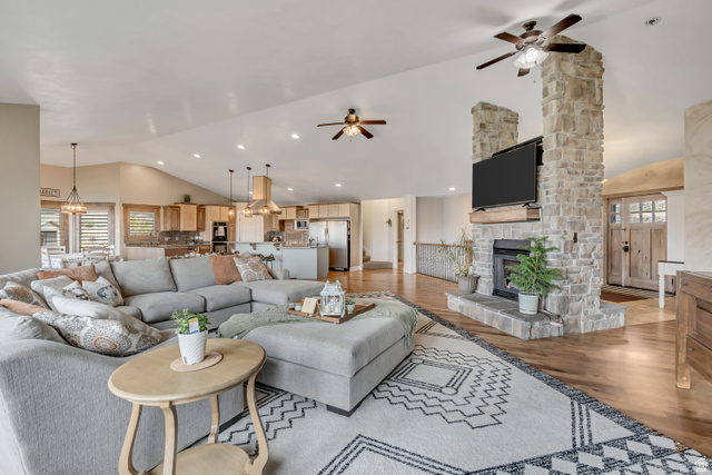 3054 West Ridgeline Road Stockton, UT 84071 - Photo 32 of 88 Living room featuring vaulted ceiling, light wood-type flooring, ceiling fan, suspended lighting, and a stone fireplace