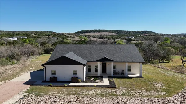 an aerial view of a house with a yard and trees in the background