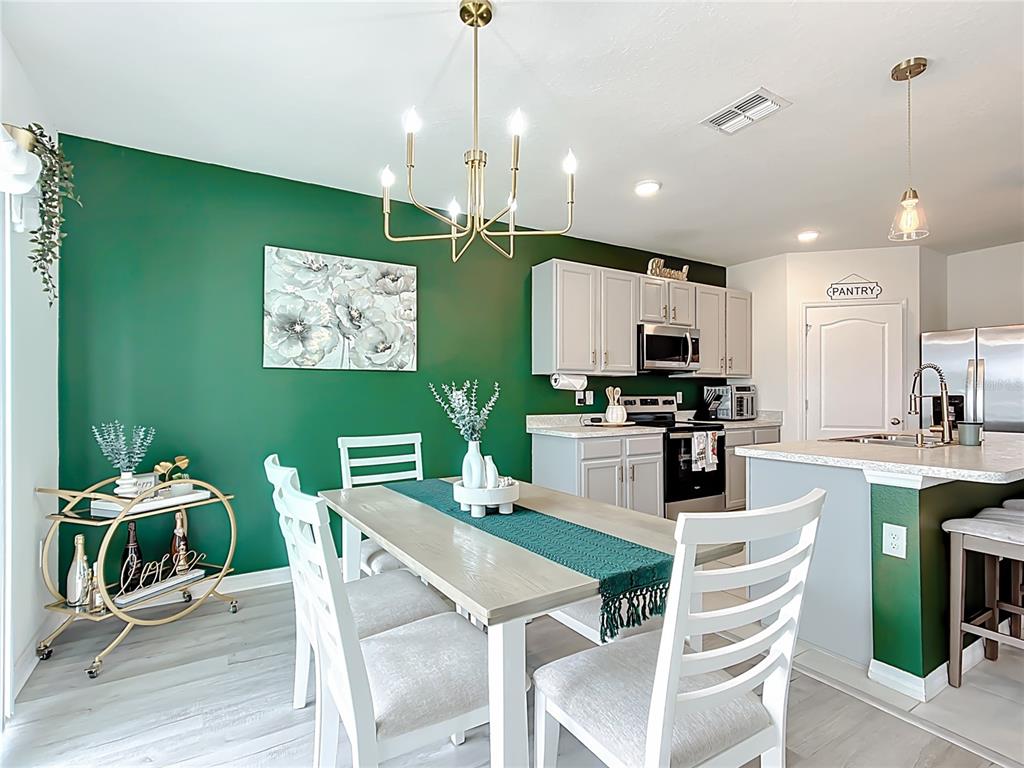 605 Honey Bell Road Winter Haven, FL 33880 - Photo 24 of 71 a kitchen with stainless steel appliances kitchen island granite countertop a dining table chairs and a refrigerator