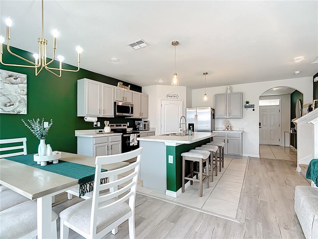 605 Honey Bell Road Winter Haven, FL 33880 - Photo 27 of 73 a kitchen with stainless steel appliances kitchen island granite countertop a table chairs and a refrigerator