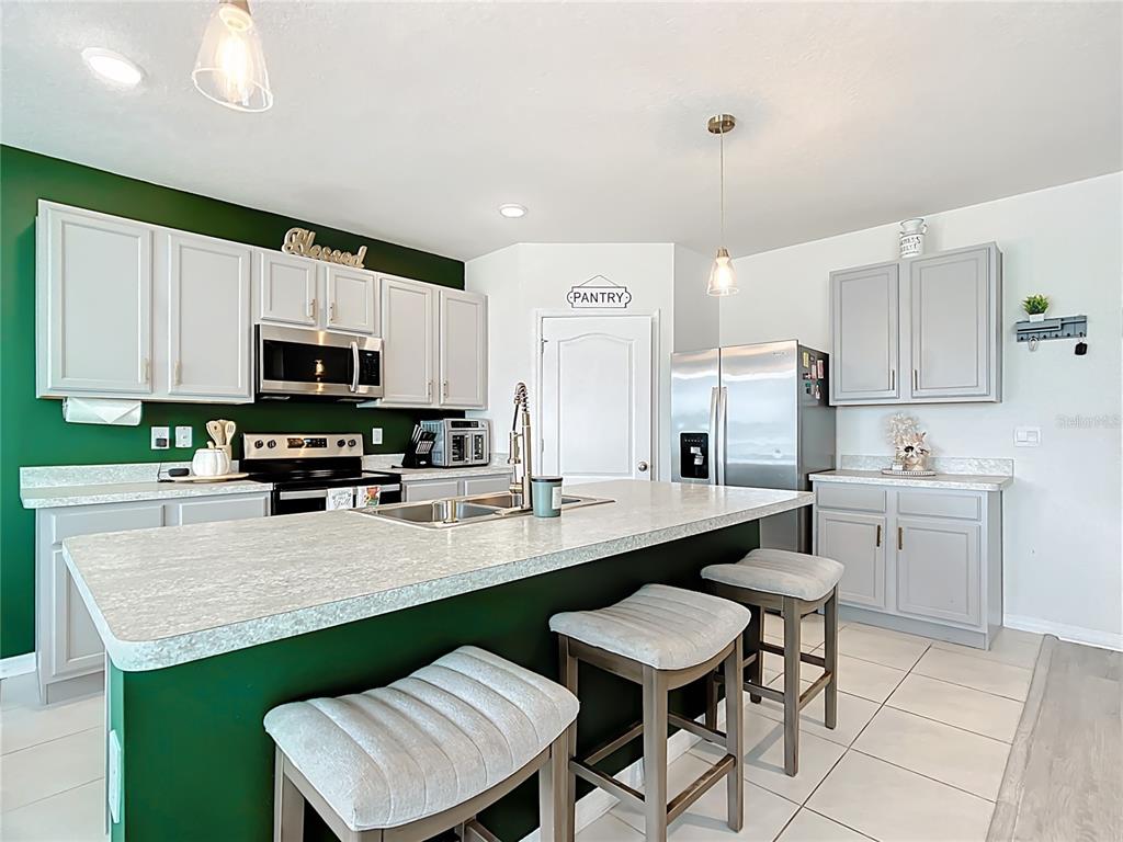 605 Honey Bell Road Winter Haven, FL 33880 - Photo 28 of 73 a kitchen with stainless steel appliances a sink a stove a refrigerator cabinets and chairs