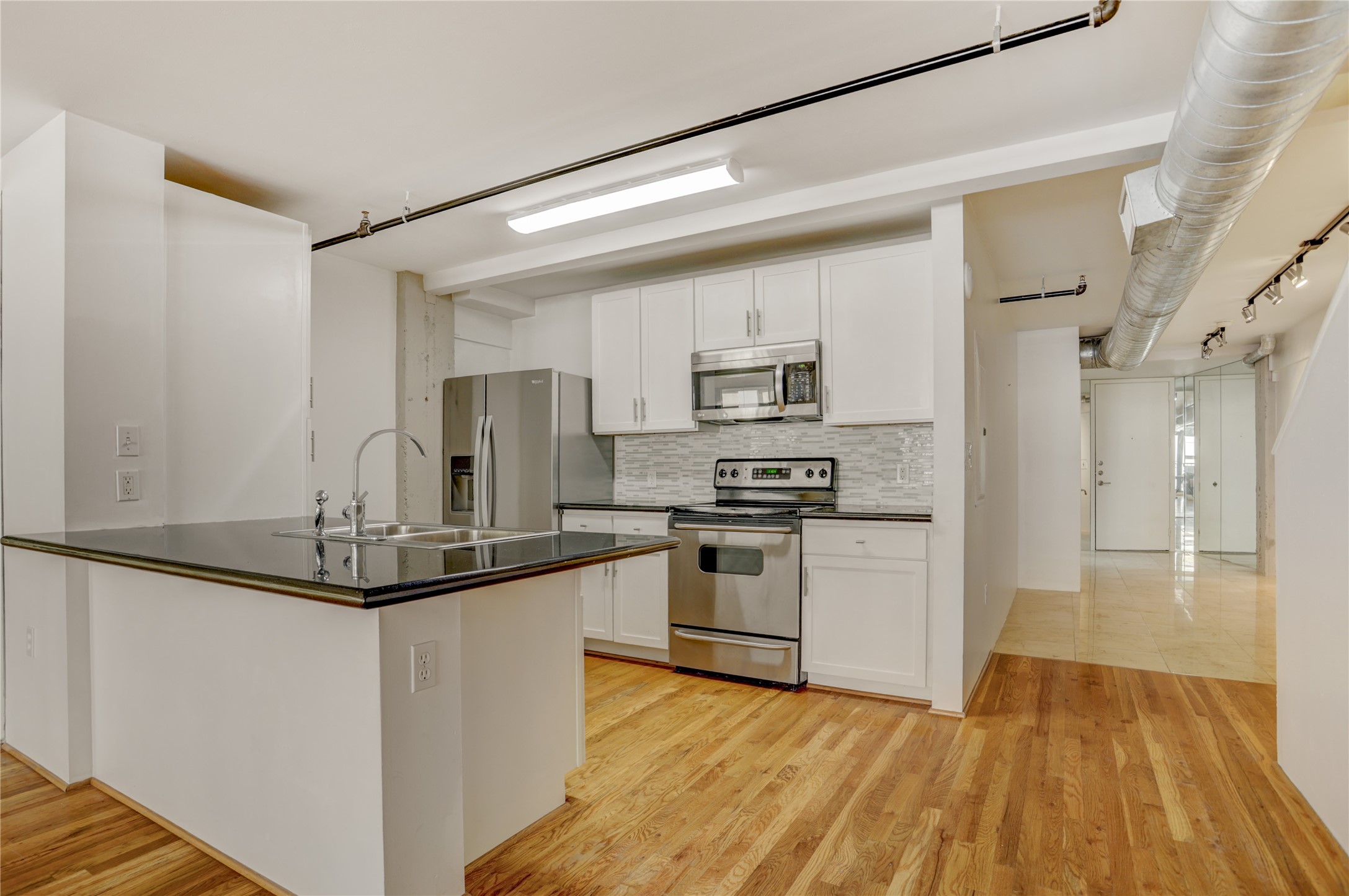 917 Main Street, Unit 1107 Houston, TX 77002 - Photo 6 of 33 a kitchen with kitchen island granite countertop a sink cabinets and stainless steel appliances