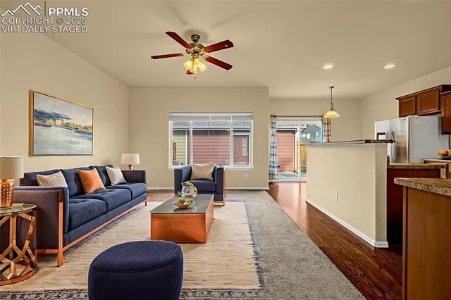 a living room with stainless steel appliances furniture a couch and a kitchen view