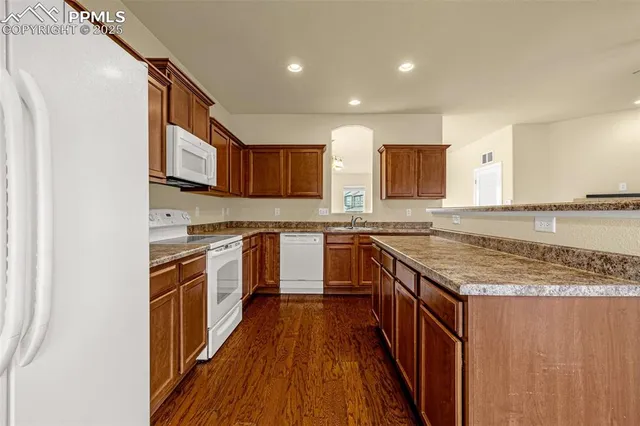 a kitchen with stainless steel appliances granite countertop a stove top oven a sink and dishwasher with wooden floor