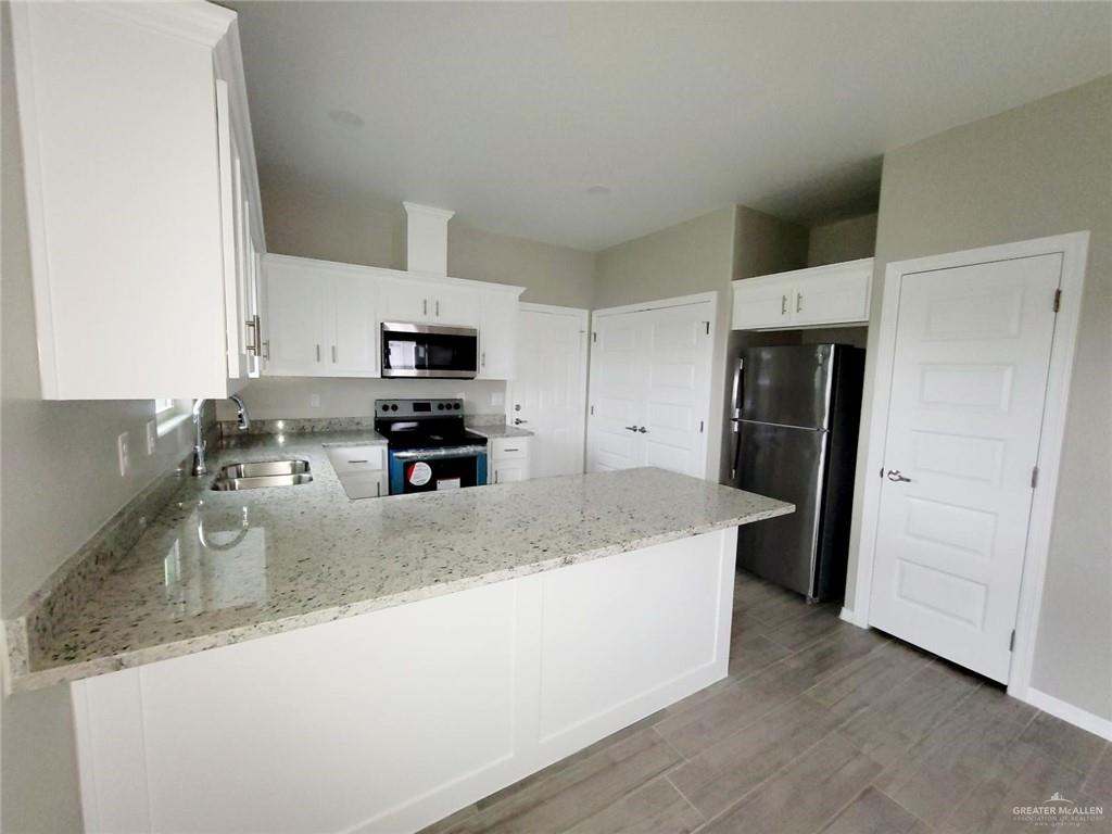 1805 Davenport Street, Unit 1 Weslaco, TX 78596 - Photo 12 of 20 a kitchen with granite countertop a refrigerator and a sink