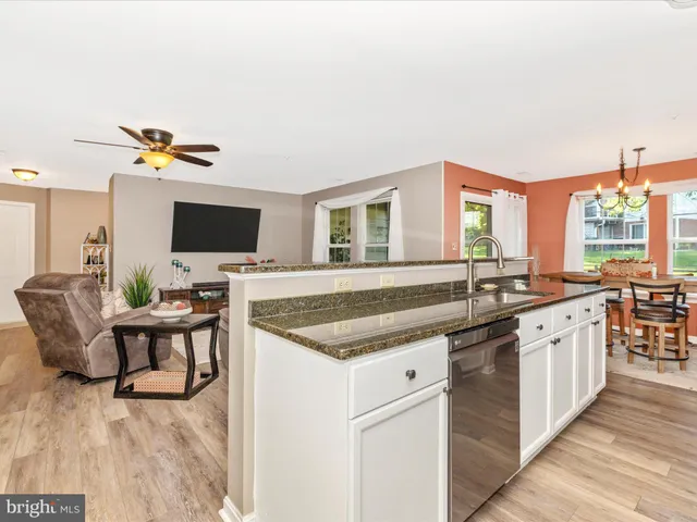 a large kitchen with granite countertop a large counter top space a sink stainless steel appliances and cabinets