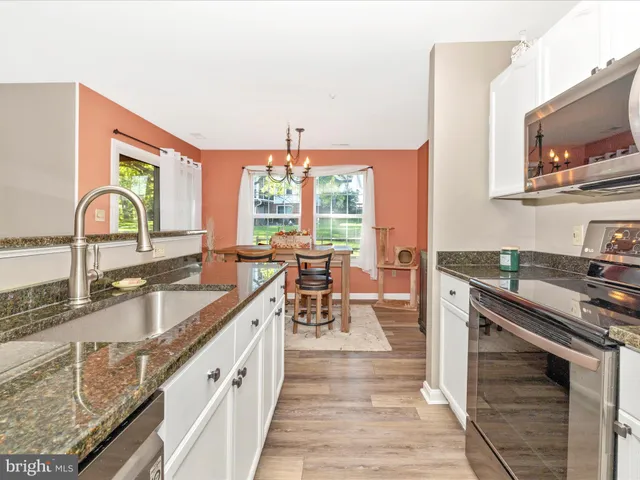 a kitchen with granite countertop a sink stainless steel appliances and cabinets