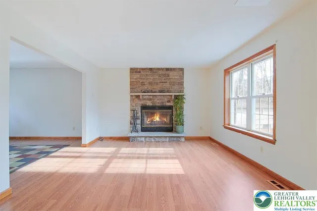 a view of an empty room with a window and fire place