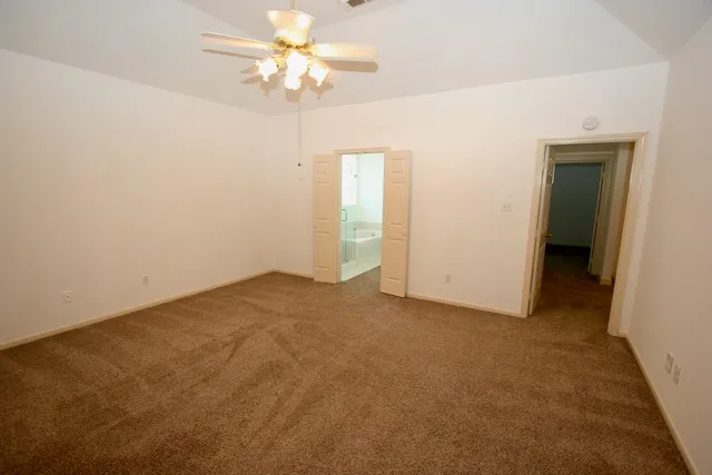 an empty room with a ceiling fan and a bathroom