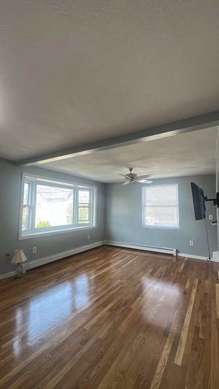 155 Cottage Street, Unit 2 Everett, MA 02149 - Photo 2 of 8 an empty room with wooden floor and windows