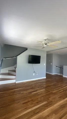 a view of a room with a ceiling fan and wooden floor