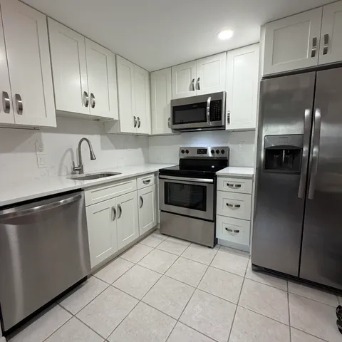 a kitchen with white cabinets stainless steel appliances and a sink