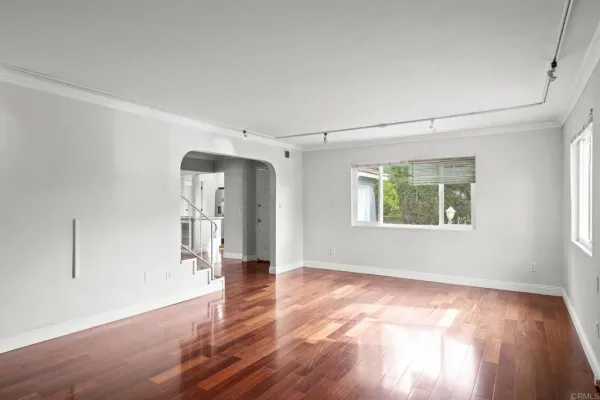 a view of an empty room with window and wooden floor