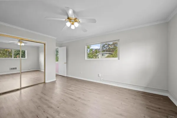 a view of an empty room with a window and wooden floor