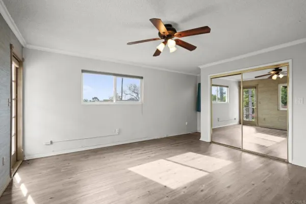 a view of empty room with wooden floor and fan