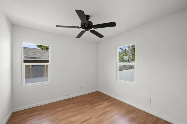 an empty room with wooden floor closet and fan