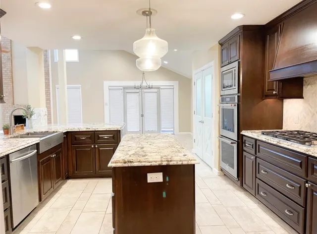 a kitchen with stainless steel appliances granite countertop wooden cabinets a stove a sink and a refrigerator