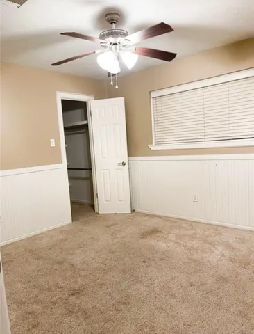 an empty room with chandelier fan and windows