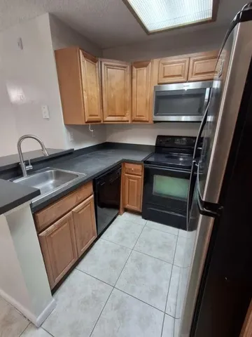 a kitchen with granite countertop a sink stove and cabinets