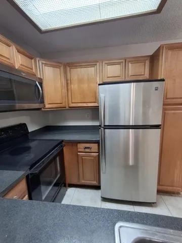 a kitchen with stainless steel appliances granite countertop a refrigerator a sink and a stove