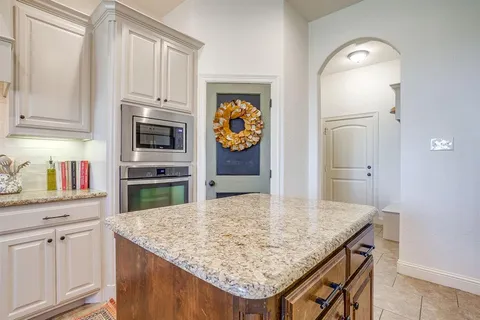 a kitchen with granite countertop a sink stainless steel appliances and white cabinets