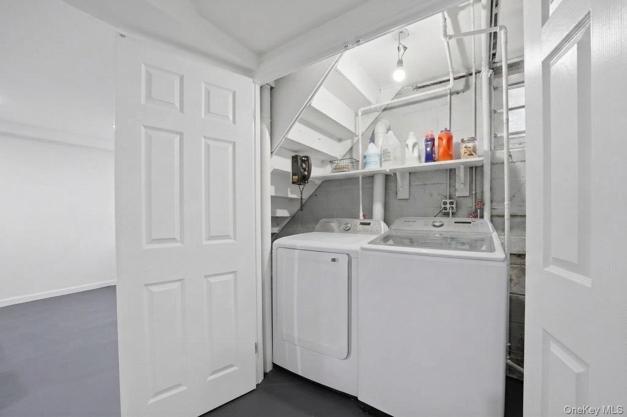 144 Bell Road Scarsdale, NY 10583 - Photo 36 of 49 Dedicated laundry area featuring a washer and dryer, under-stair storage shelving, and exposed utility piping