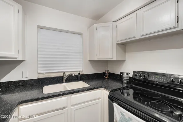 a kitchen with granite countertop a stove and a white cabinets
