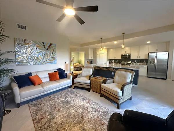 a living room with furniture kitchen view and a chandelier