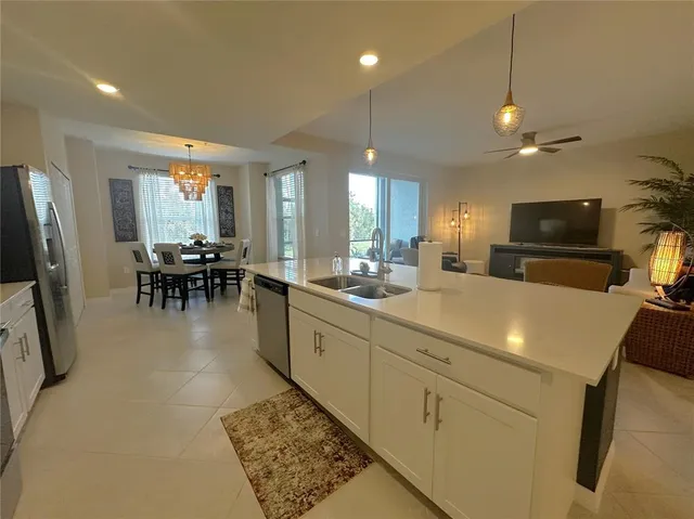 a kitchen with stainless steel appliances granite countertop a sink dishwasher a stove a refrigerator a dining table and chairs with wooden floor