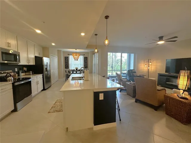 a large kitchen with kitchen island a large counter top stainless steel appliances and cabinets