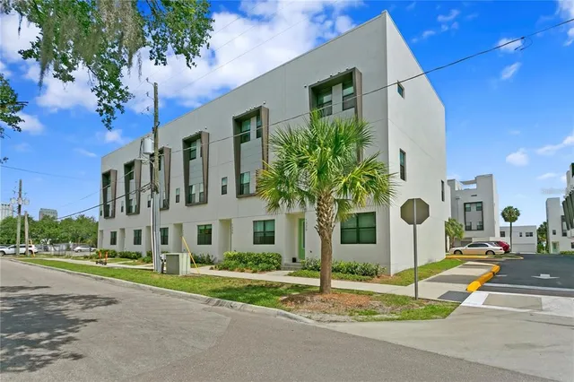 a view of a white building among the street with palm trees