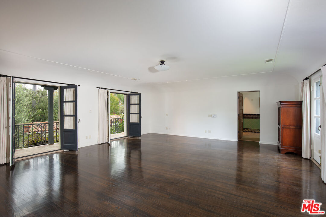 703 Walden Drive Beverly Hills, CA 90210 - Photo 13 of 22 a view of an empty room with wooden floor and a window