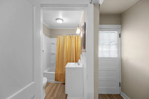 a view of a hallway with wooden floor and a bathroom