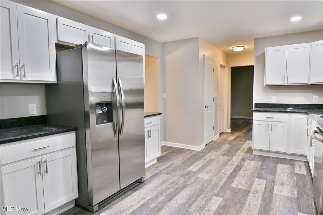 Kitchen with white cabinetry, light wood-type flooring, and appliances with stainless steel finishes