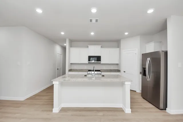 a kitchen with kitchen island a sink stainless steel appliances and refrigerator