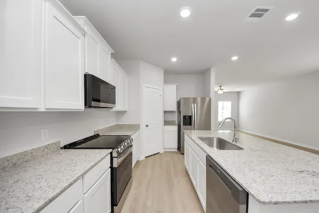 a kitchen with stainless steel appliances granite countertop a sink a stove and a refrigerator