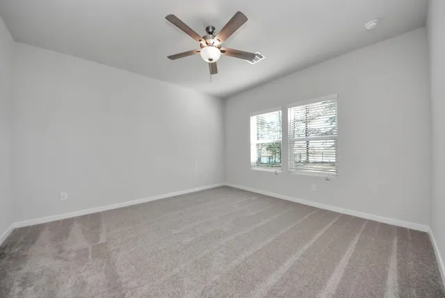an empty room with windows and fan