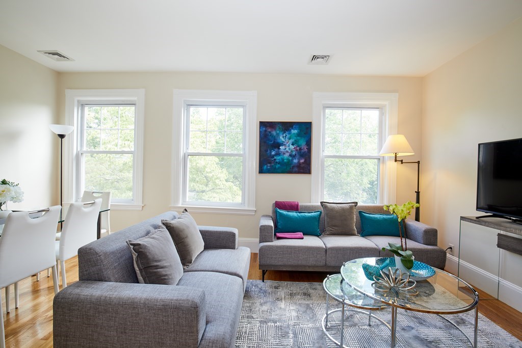 a living room with furniture a large window and a flat screen tv