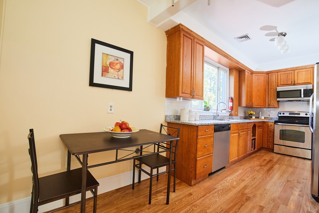 92 Coolidge Street, Unit 2 Brookline, MA 02446 - Photo 8 of 29 a kitchen with stainless steel appliances granite countertop a stove a sink dishwasher and a refrigerator with wooden floor